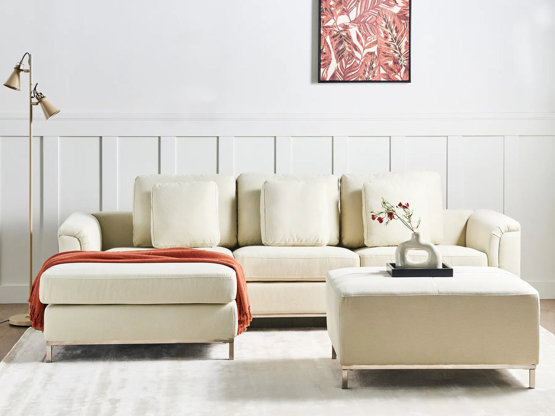Beige sectional sofa with a matching ottoman in a living room setting.
