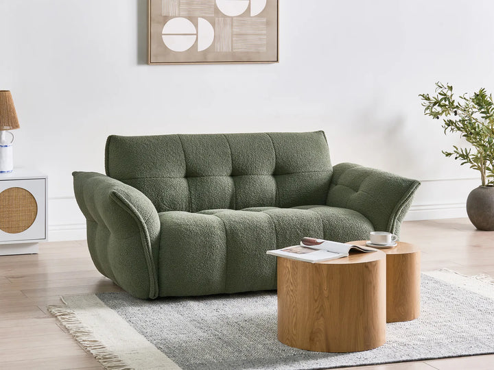 Green sofa in a living room with wooden tables and decor