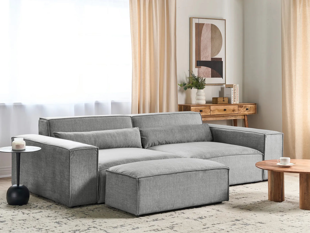 Gray sectional sofa in a living room setting with a coffee table and decorative items.