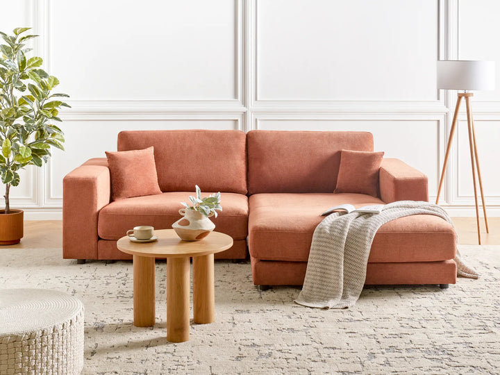 Coral sectional sofa in a living room with a small table and decor items.