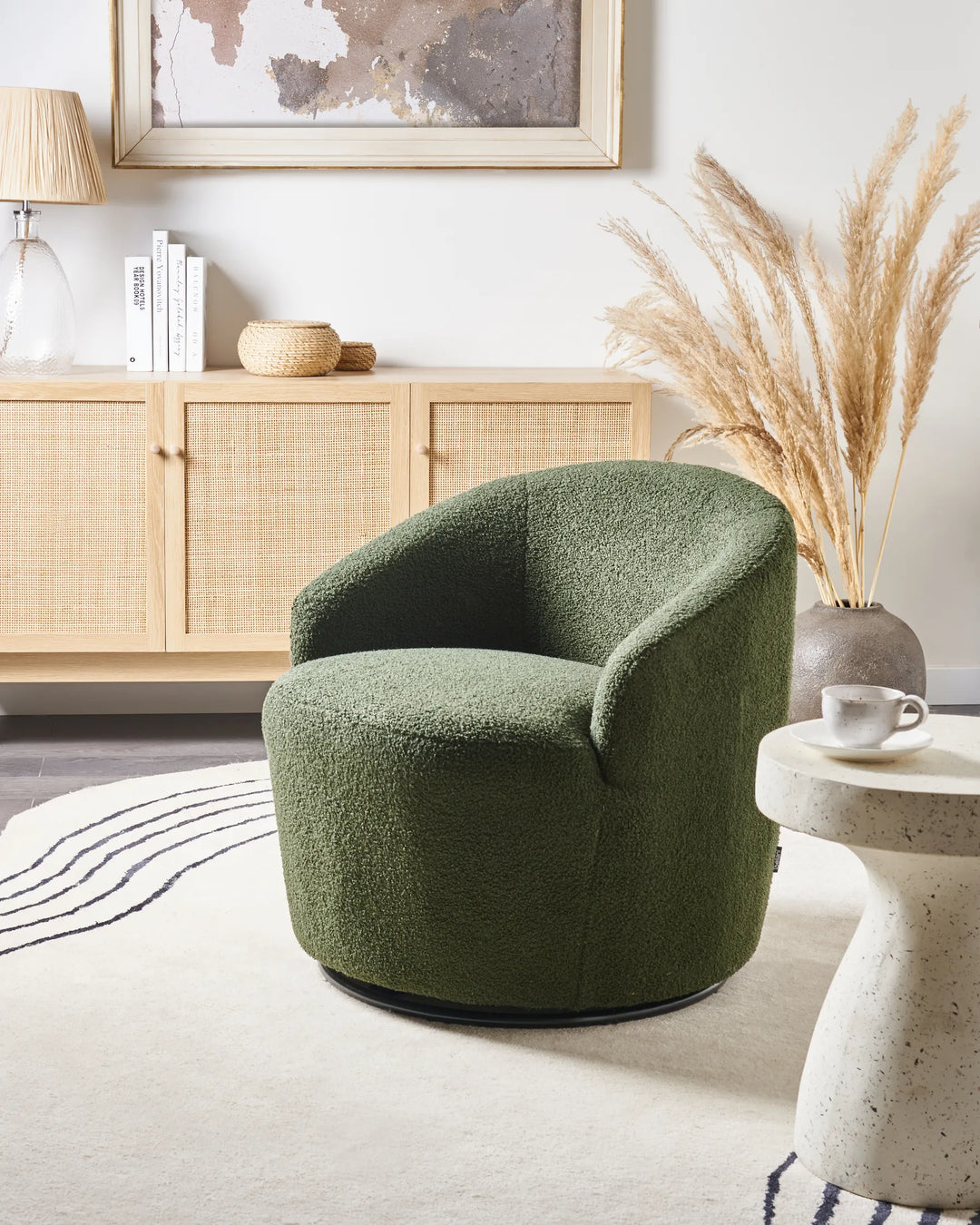 Green armchair in a living room with a wooden sideboard and decorative elements.