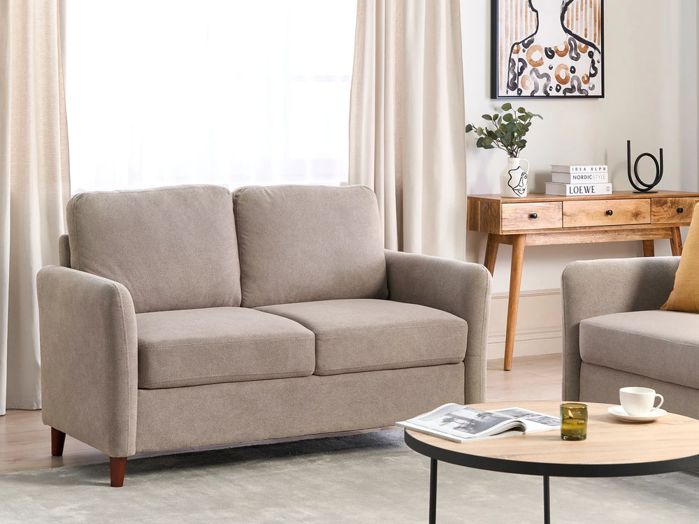 Beige sofa in a living room setting with a coffee table and decorative items.