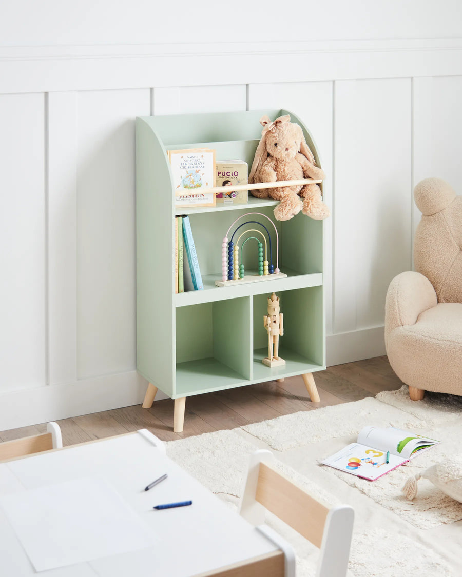 Children's room with a green bookshelf, teddy bear, and toys.