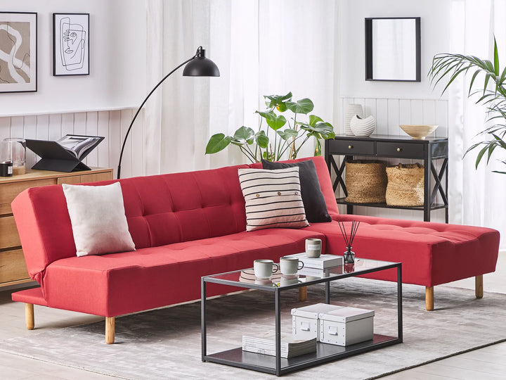 Red sectional sofa in a living room with a coffee table and decor items.