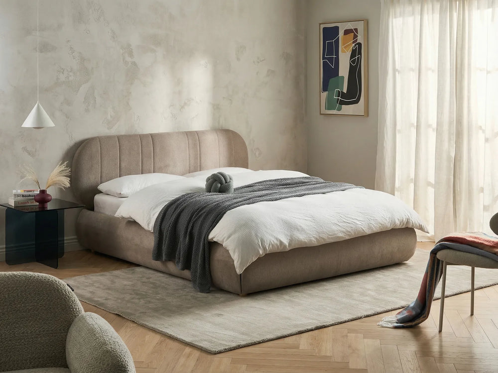 Beige upholstered bed in a modern bedroom with neutral decor