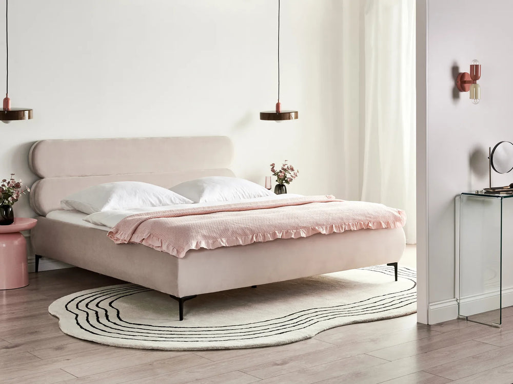 Neatly made bed with pink bedding in a modern bedroom setting.
