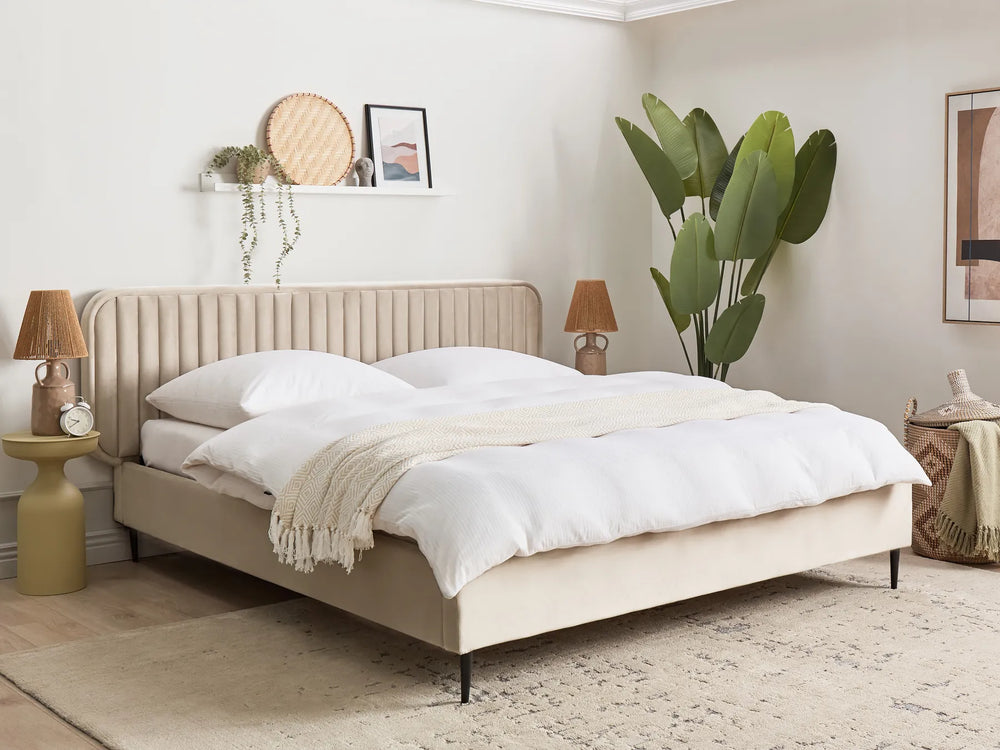Beige upholstered bed in a bedroom with white bedding and decorative elements.