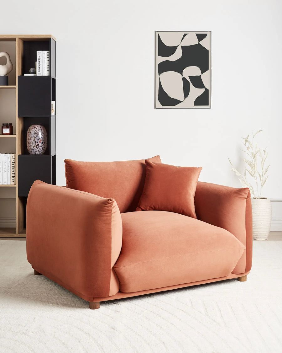Coral sofa in a modern living room with a bookshelf and abstract art on the wall.