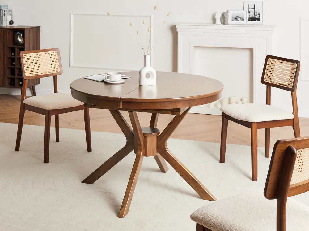 Round wooden dining table with four chairs in a room with a fireplace.