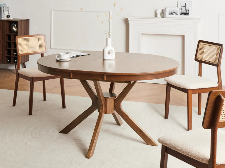 Wooden dining table with four chairs in a room with a fireplace.