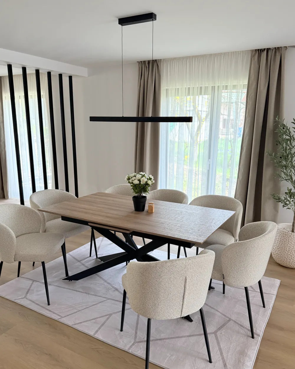 Modern dining room with a wooden table and beige chairs, featuring a pendant light and large windows.