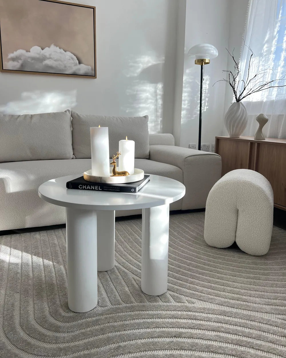 Modern living room with a white coffee table, candles, and decor items.
