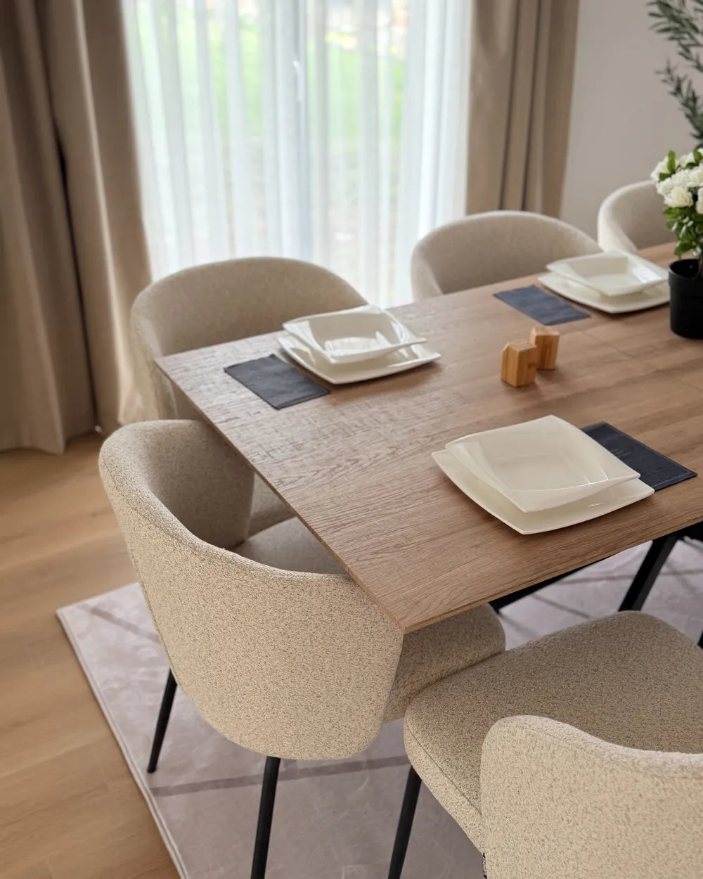 Dining table set with plates and placemats in a well-lit room.