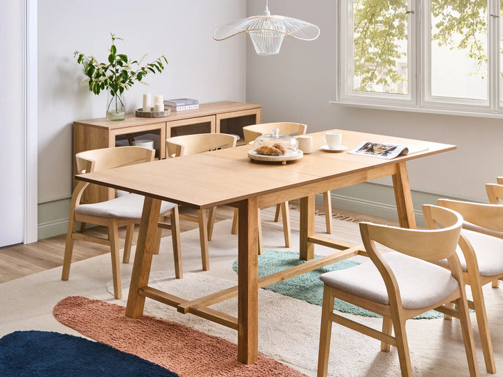 Dining room with wooden table and chairs in a well-lit room.