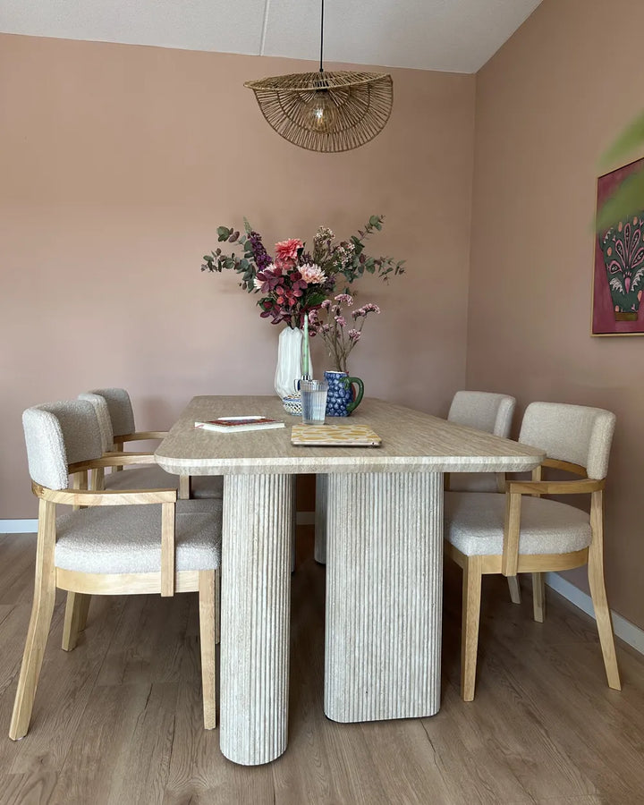 Dining room with a marble table and chairs, featuring a vase of flowers on the table.