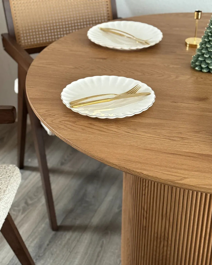 Dining table with white plates and gold cutlery in a home setting