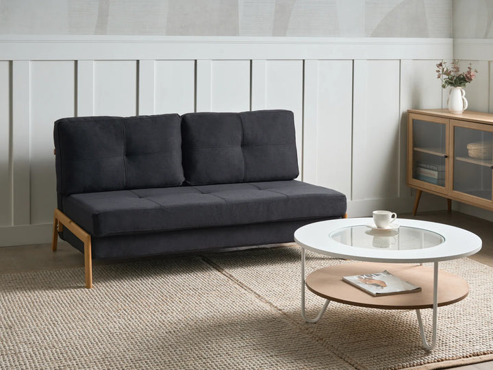 Dark gray sofa in a living room with a white coffee table and wooden cabinet.