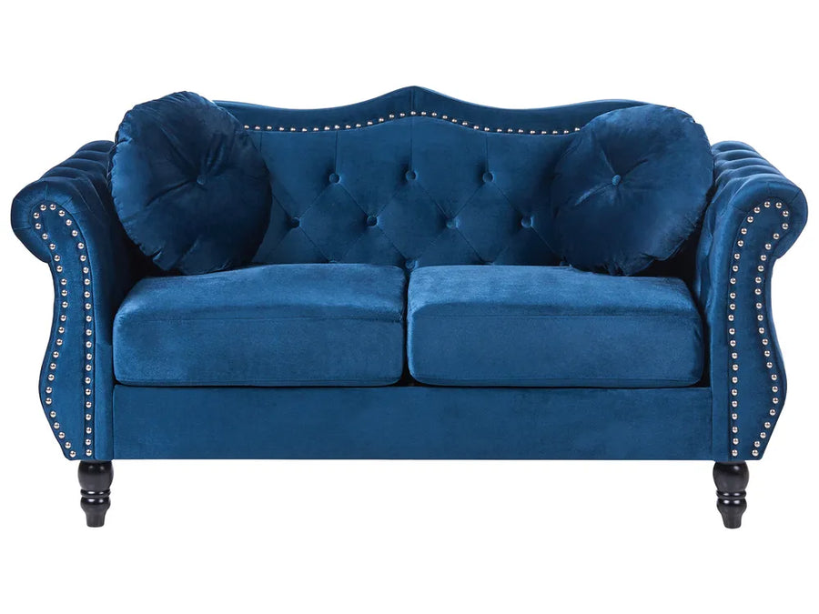 Blue velvet sofa with tufted backrest and nailhead trim on a white background