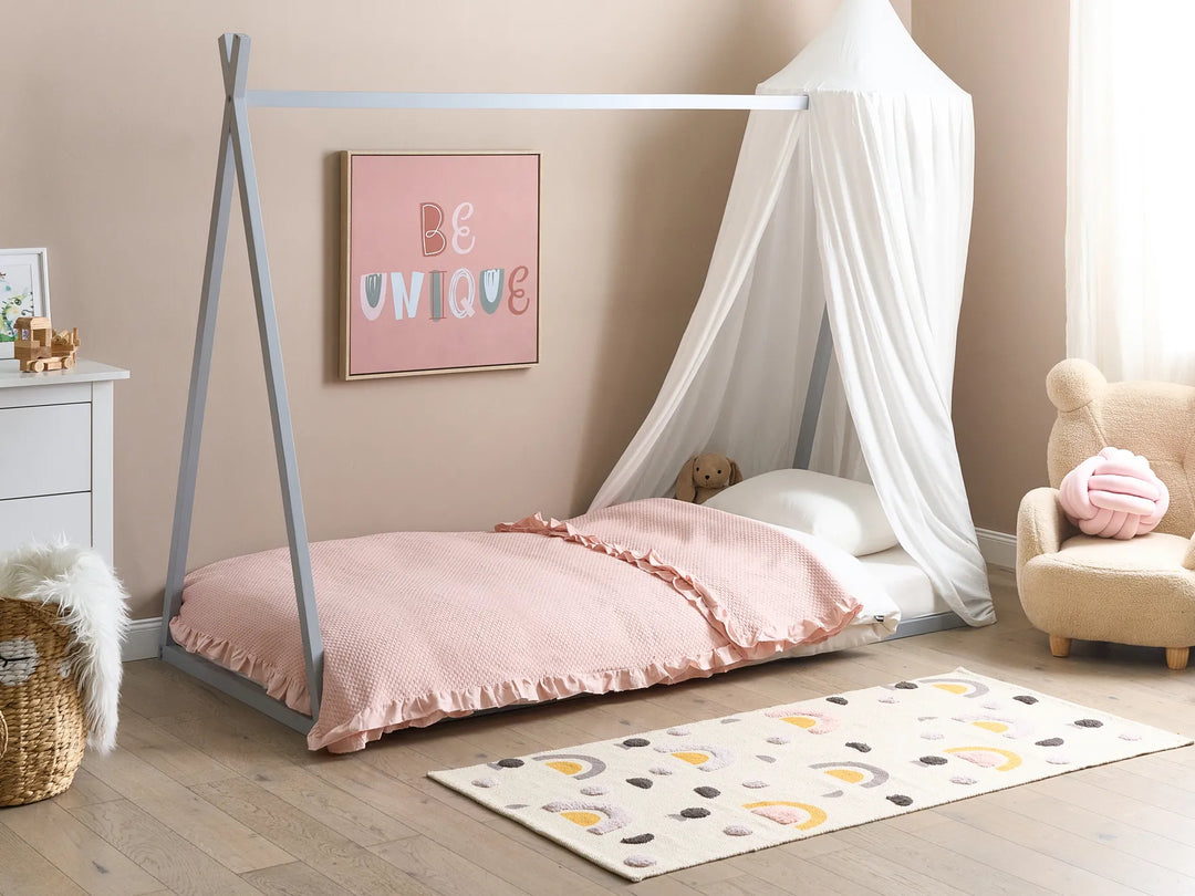 Children's room with a teepee bed, pink bedding, and decorative elements.
