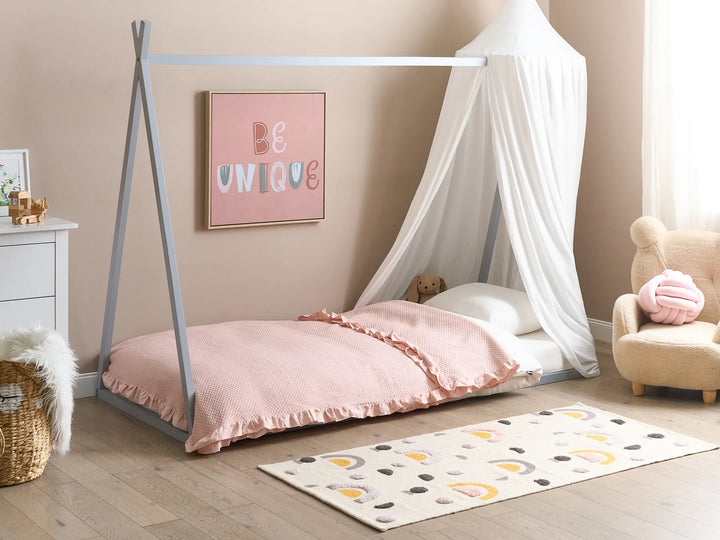 Children's room with a teepee bed, pink bedding, and decorative elements.