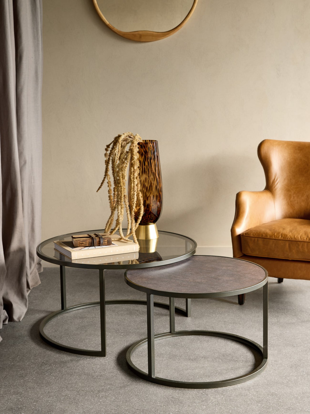 Modern living room with round glass coffee table and brown leather armchair.