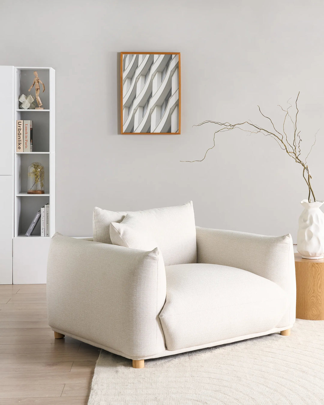 White armchair in a modern living room with a abstract wall art and minimal decor.