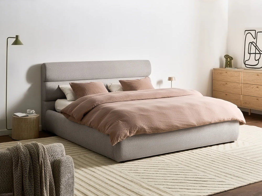 Neatly made bed with pink bedding in a modern bedroom setting.
