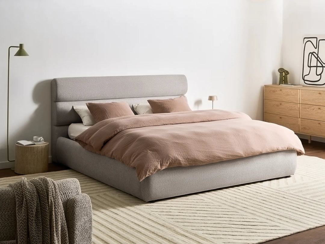 Neatly made bed with pink bedding in a modern bedroom setting.