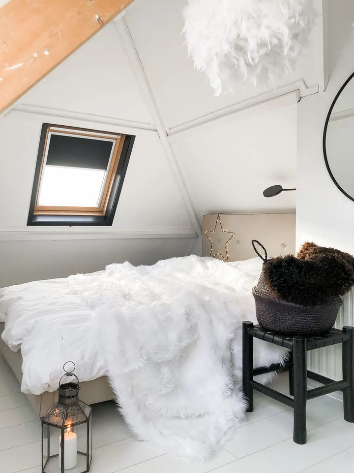 Cozy bedroom with white bedding, a candle lantern, and decorative items.