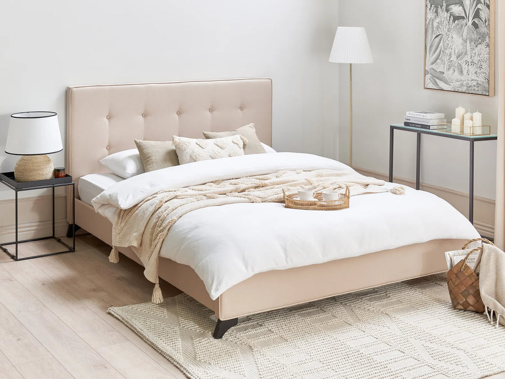 Beige upholstered bed in a modern bedroom with white bedding and decorative pillows.