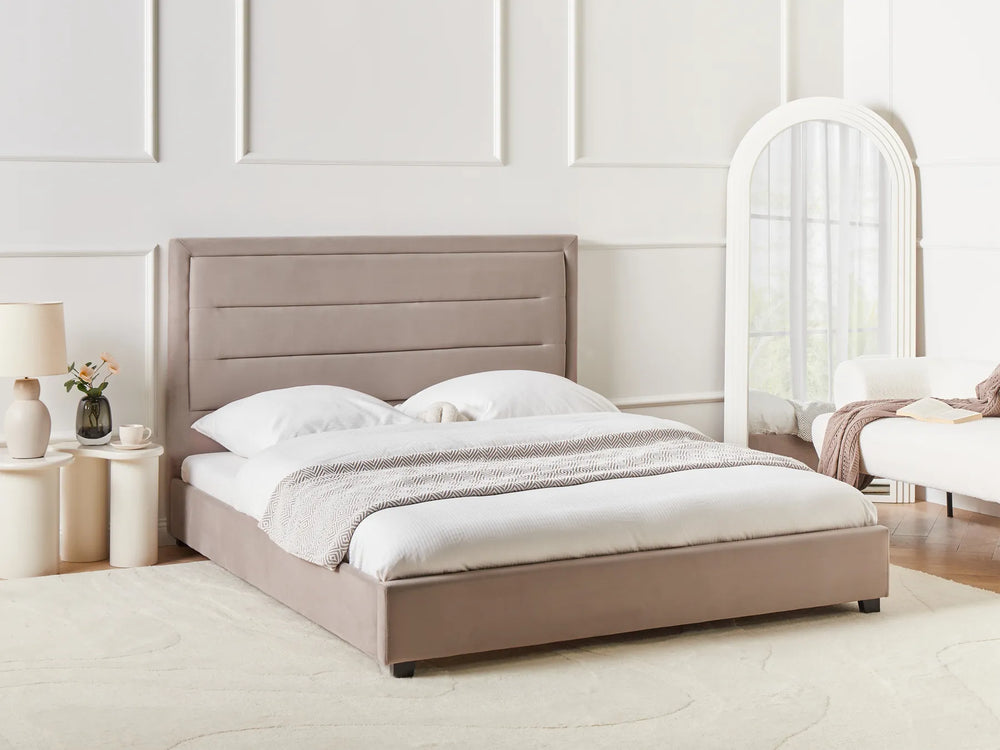Beige upholstered bed in a bedroom setting with a mirror and nightstands.