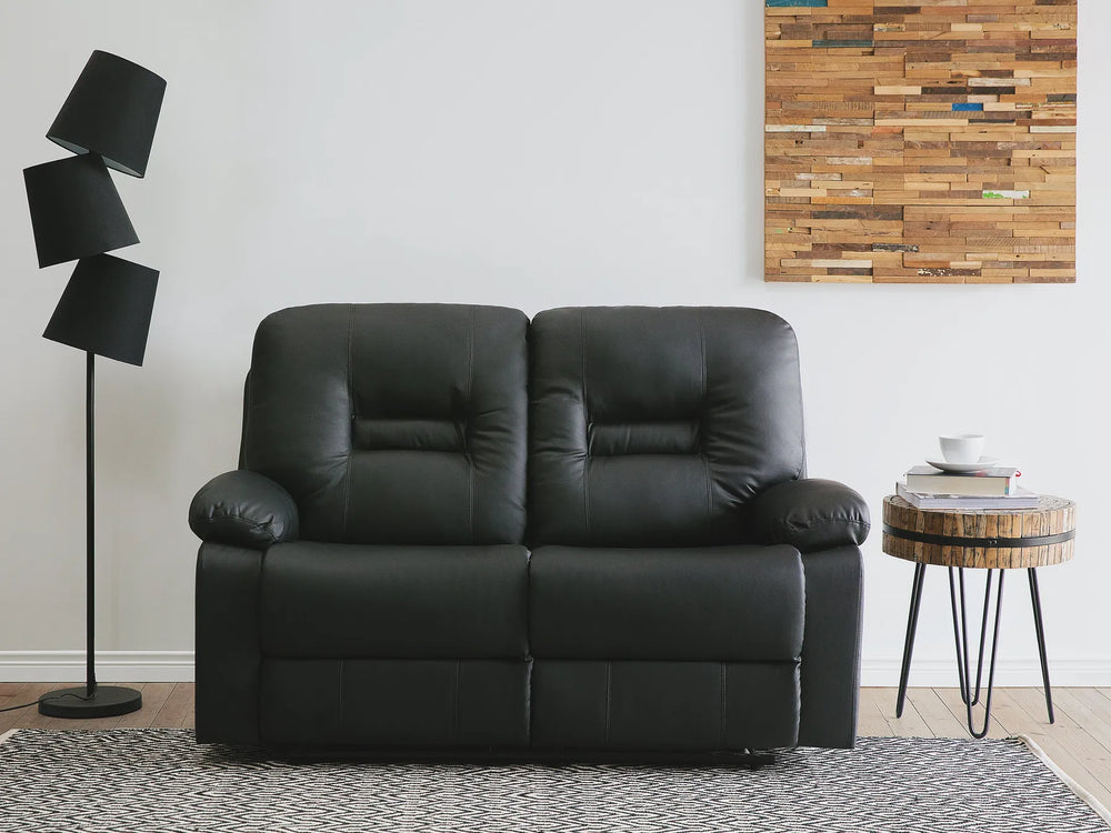 Black leather sofa in a room with a lamp and wall art.
