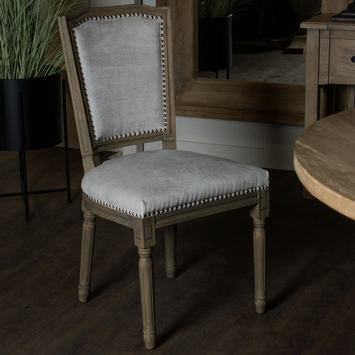 Chair with light gray cushioned seat and backrest in a dimly lit room.