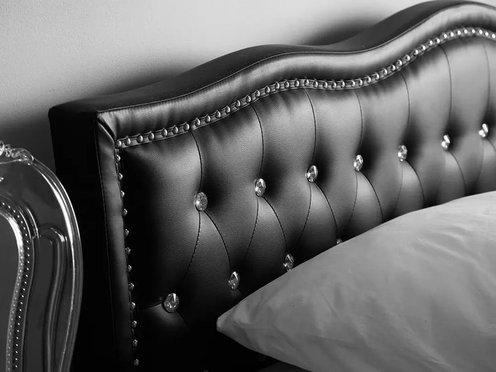 Black tufted headboard with decorative nails on a bed.