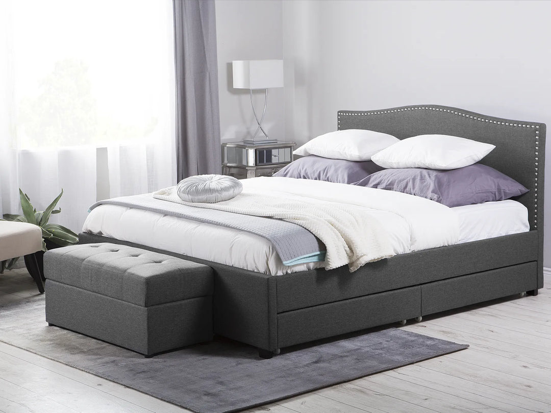 Gray upholstered bed with storage drawers in a bedroom setting.