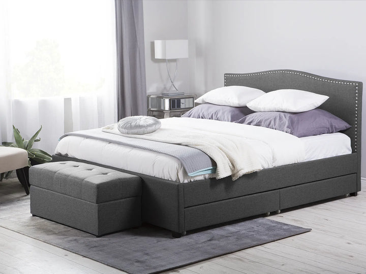Gray upholstered bed with storage drawers in a bedroom setting.