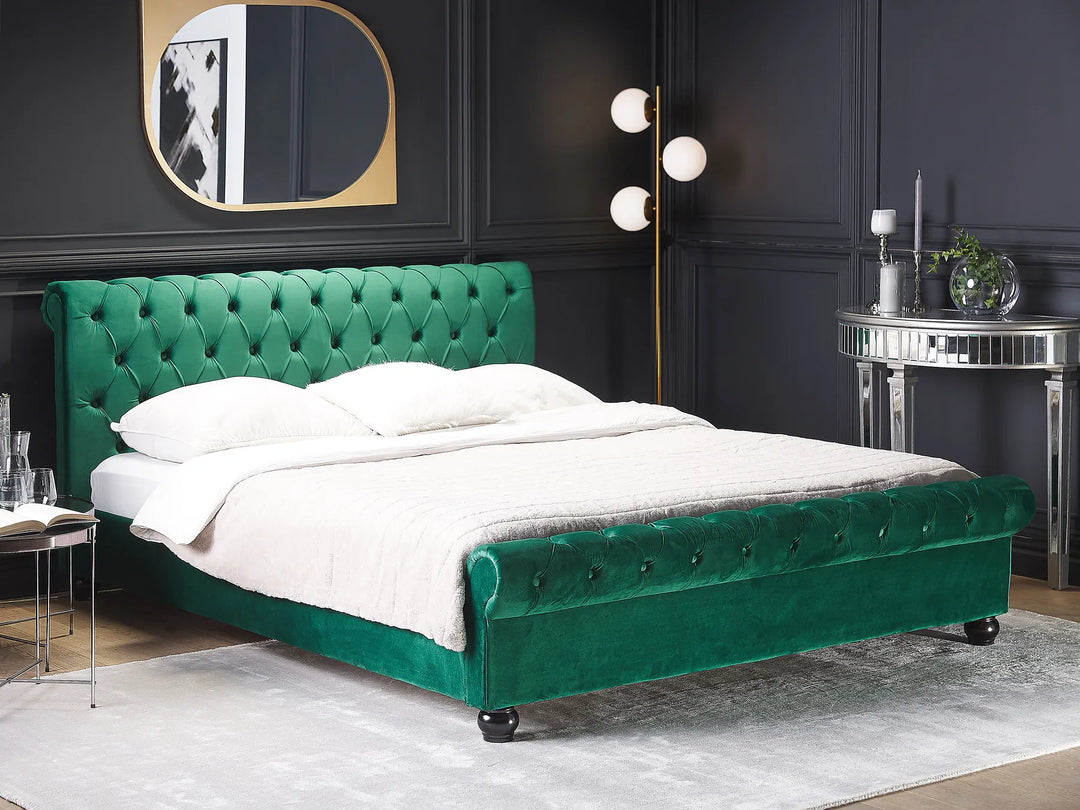 Green tufted bed in a bedroom setting with dark walls and decorative elements.