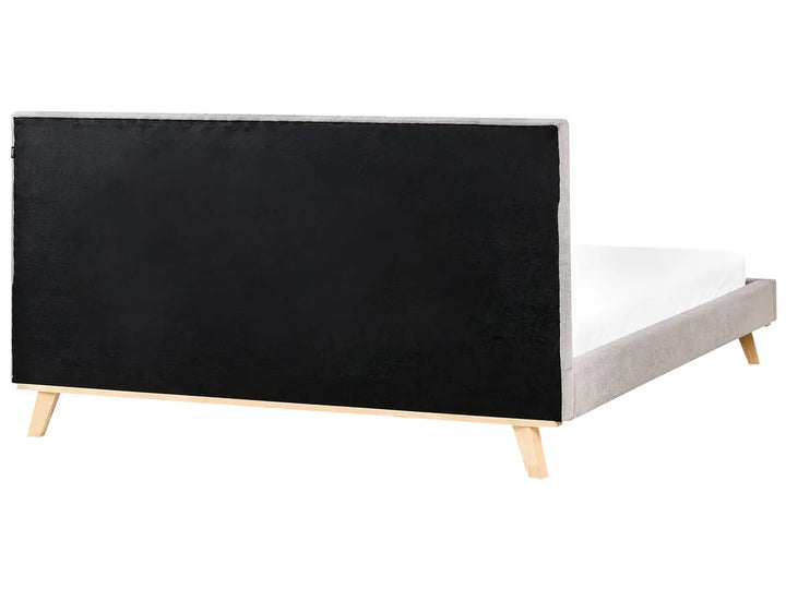 Bed with black upholstered headboard and white mattress on a white background