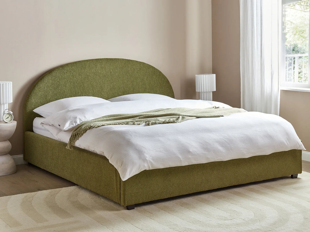 Green upholstered bed with white bedding in a bedroom setting