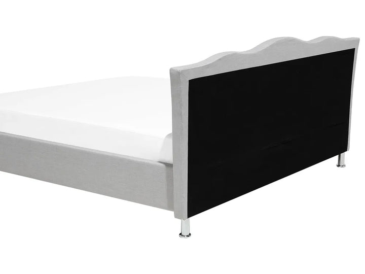 Bed with white frame and black headboard on a white background