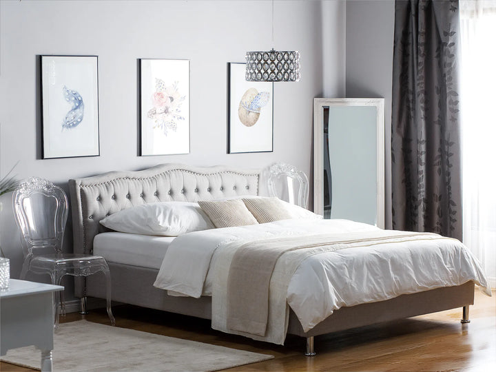 Neatly made bed in a modern bedroom with decorative pillows and a lamp.