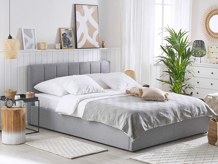 Neatly made bed with gray headboard in a bright bedroom