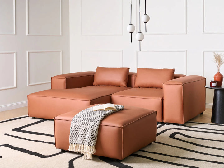 Brown leather sectional sofa in a living room with a patterned rug and decorative elements.