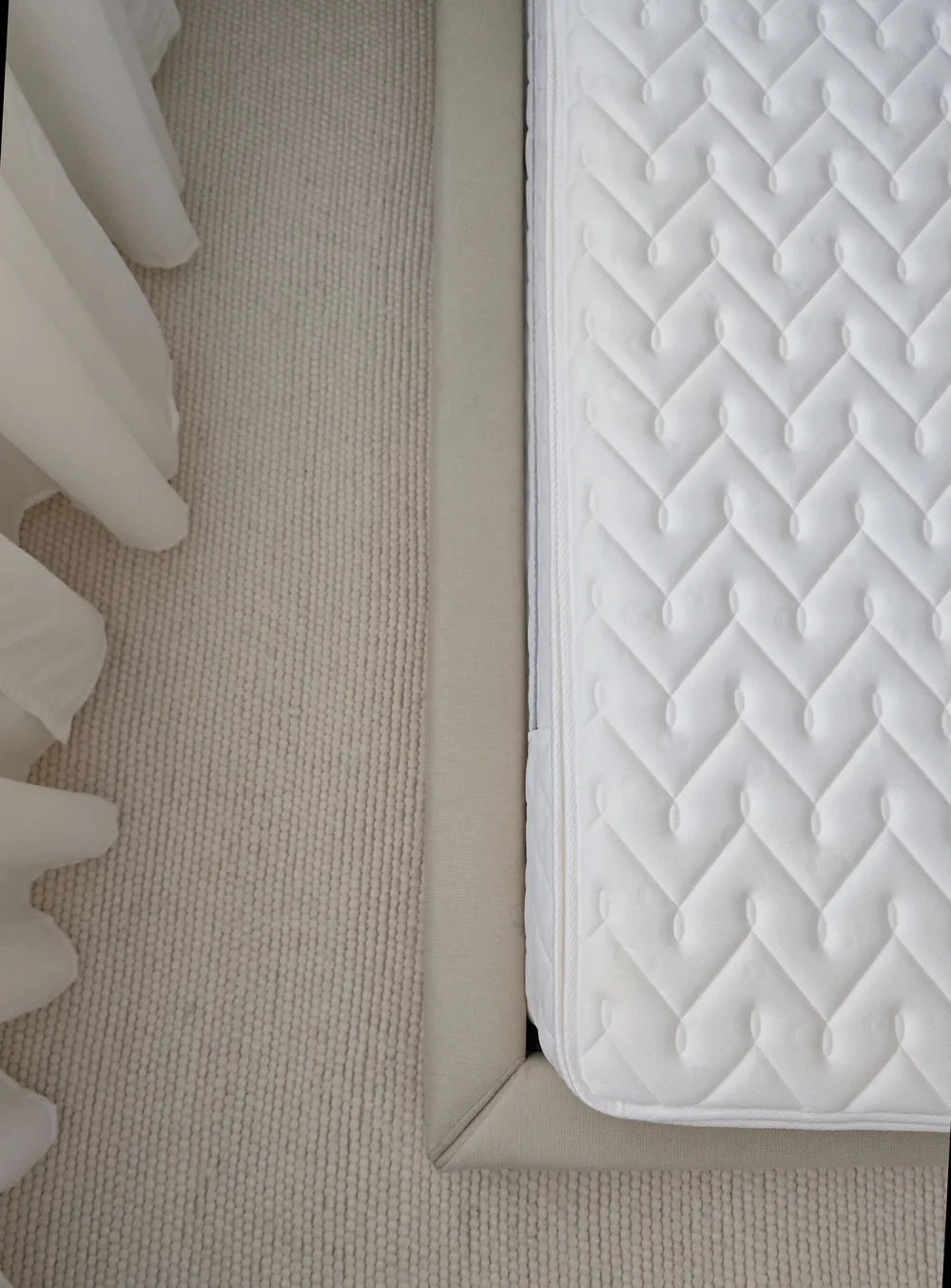 Close-up of a mattress corner with quilted design on a beige carpet