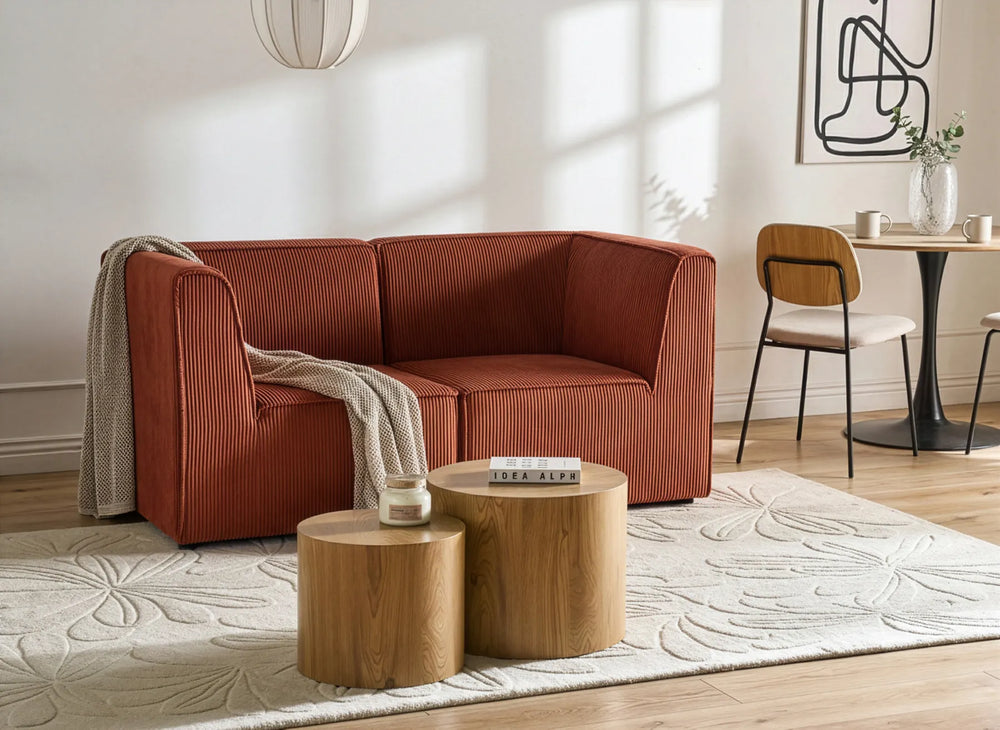 Modern living room with a red sofa, wooden tables, and a dining area.