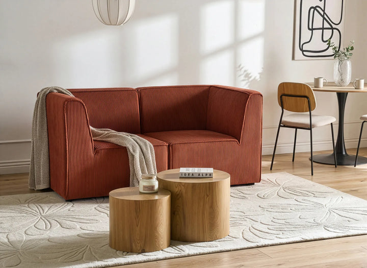 Modern living room with a red sofa, wooden tables, and a dining area.