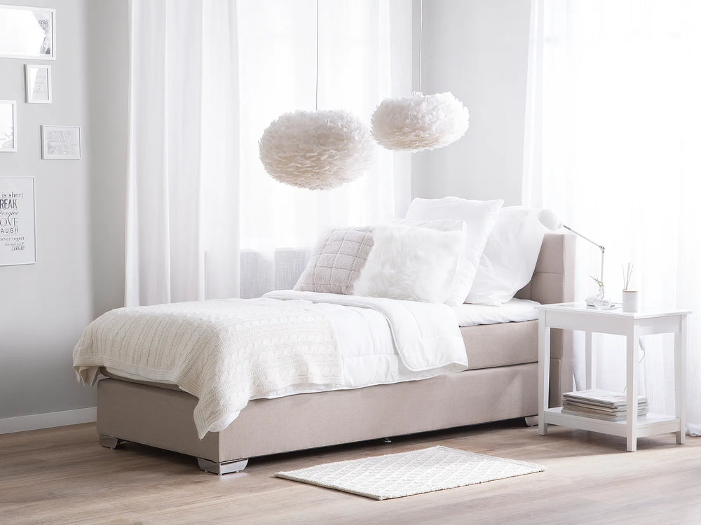 Beige bed with white bedding in a bright bedroom