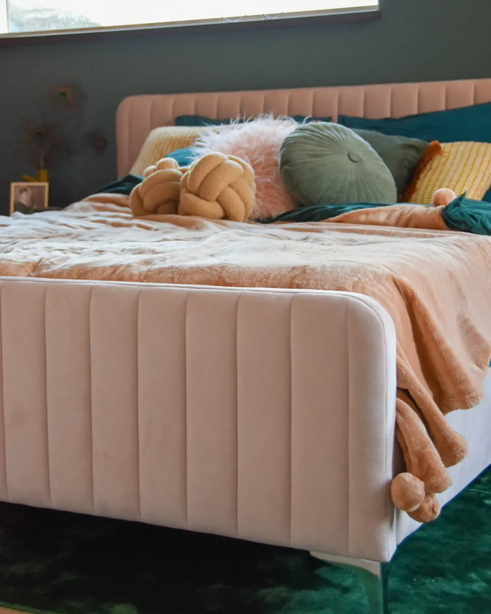 Bed with a tufted headboard and colorful pillows in a bedroom setting.