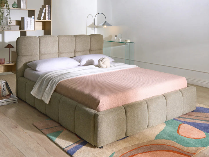 Beige upholstered bed with pink blanket in a modern bedroom setting