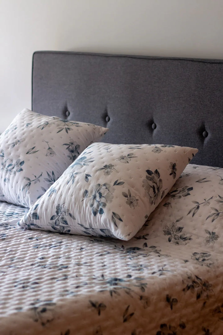Floral-patterned pillows on a bed with a tufted headboard.